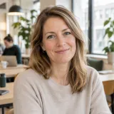 Portret van een lachende vrouw met halflang bruin haar in een lichte werkruimte